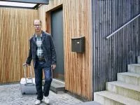 Architekt geht raus aus einem nachhaltig gebauten Gebäude und trägt einen Koffer in der Hand